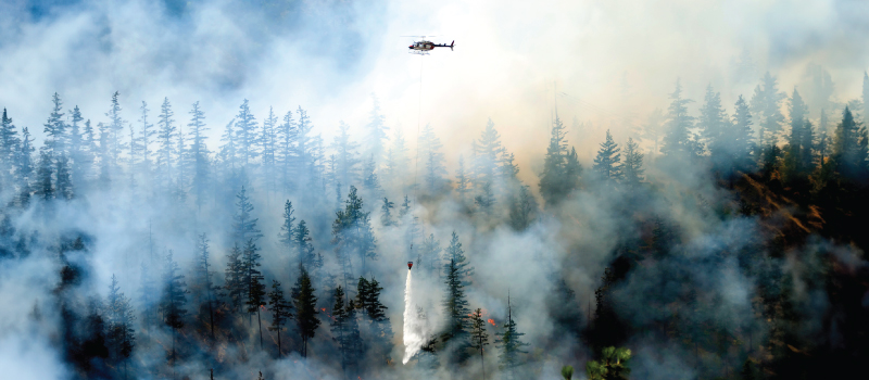 helicopter pouring water on a wildfire
