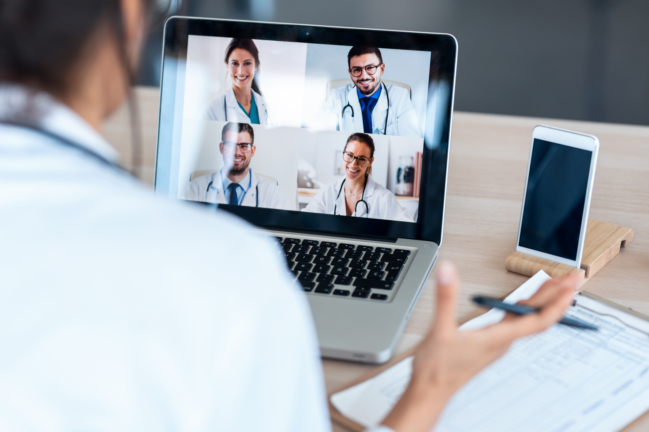 doctor with laptop during a virtual meeting with other doctors