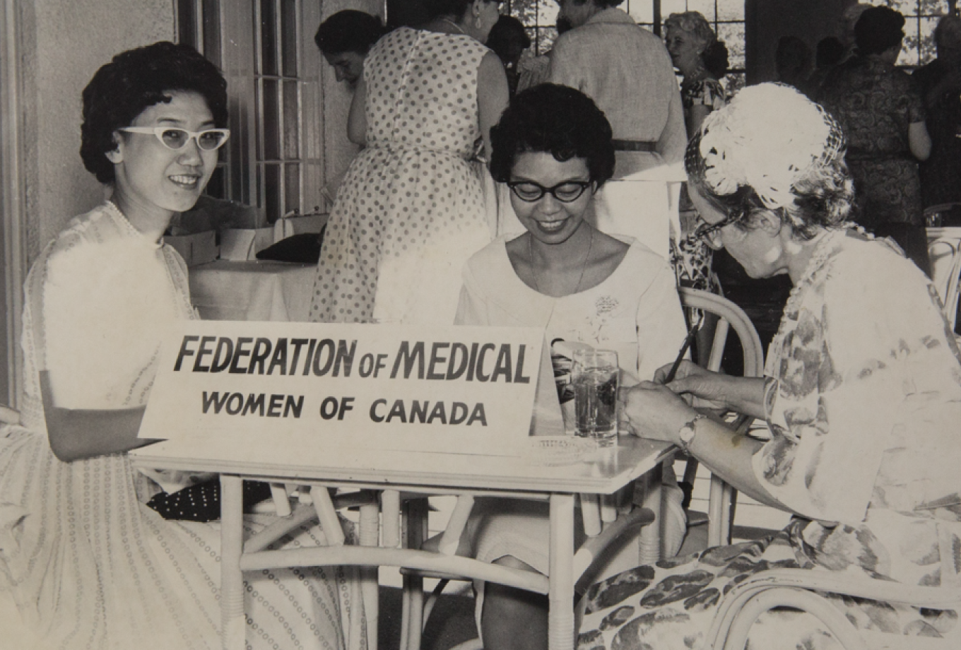 women sitting at a table with a sign on it that says Federation of Medical Women of Canada