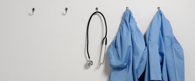 stethoscope and two scrubs hanging on a wall