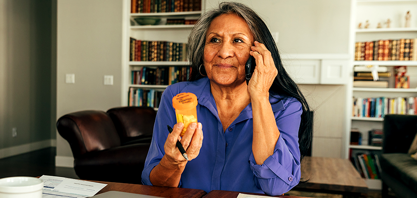 woman holding a prescription bottle while on the telephone